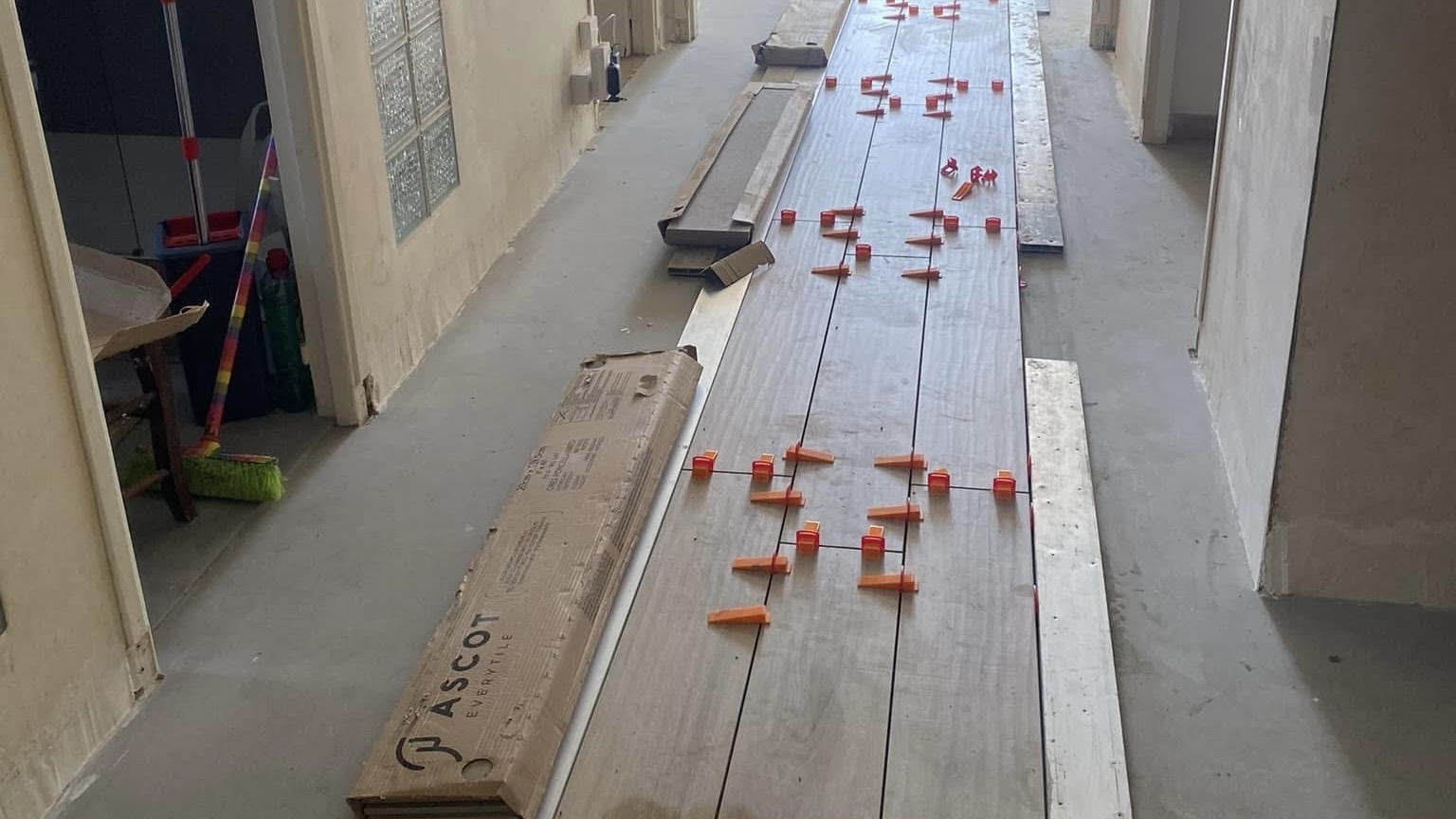 Pose de carrelage imitation bois en cours dans un couloir, avec système de cales de nivellement – Entreprise Michaël David
