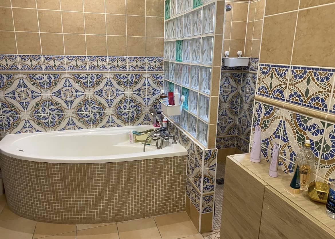 Pose de faïence murale décorative avec motifs bleus et dorés dans une salle de bain en rénovation