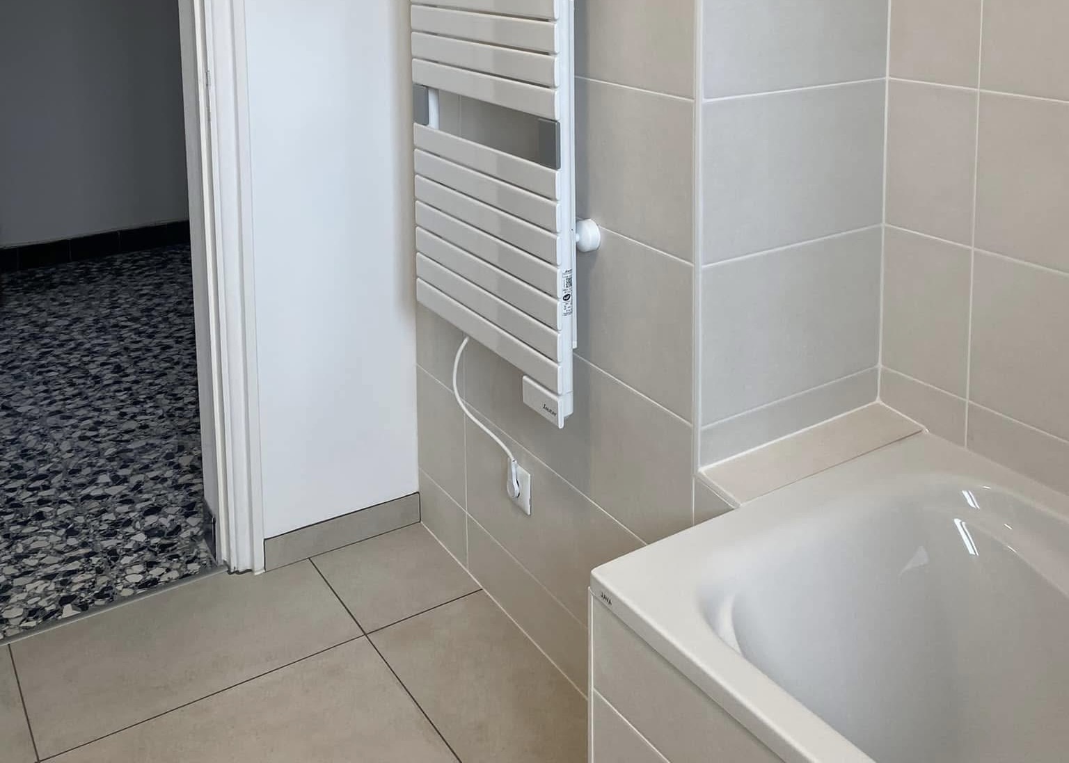 Pose de faïence beige unie dans une salle de bain moderne avec radiateur mural