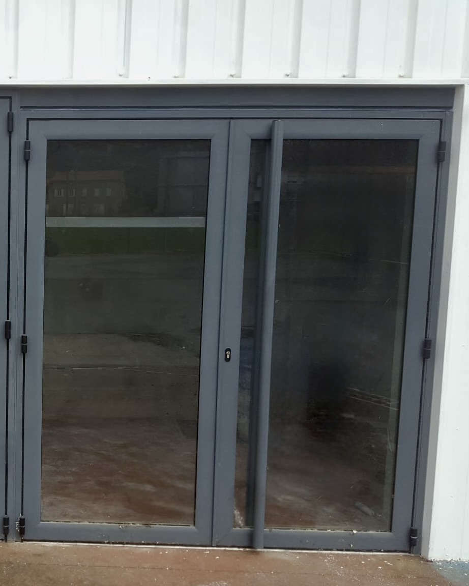Pose d’une porte-fenêtre en aluminium gris anthracite dans un bâtiment moderne
