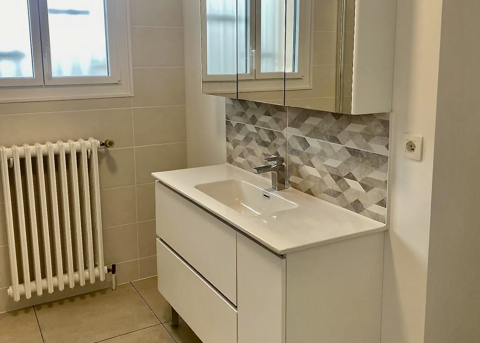 Salle de bain rénovée avec meuble vasque blanc, miroir éclairé et faïence décorative géométrique – Entreprise Michaël David