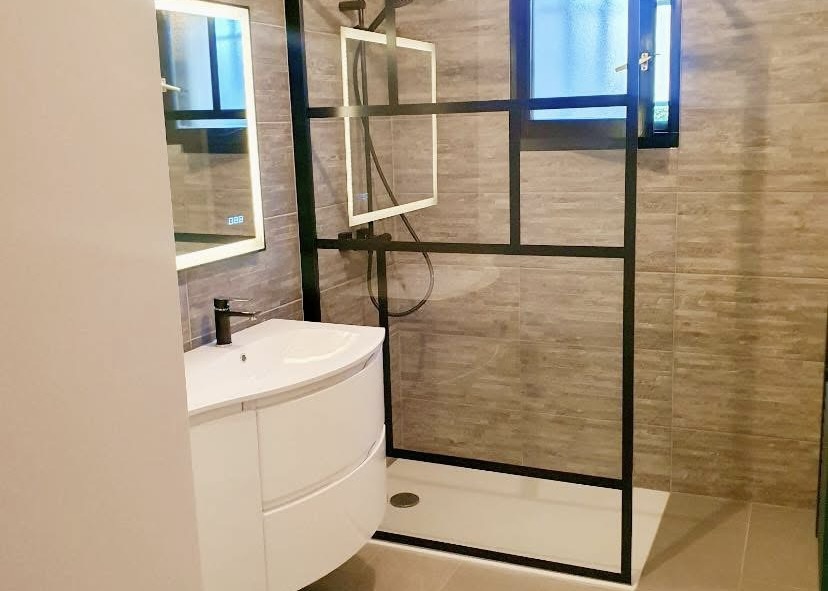 Salle de bain contemporaine avec douche à l’italienne, paroi noire et carrelage mural effet bois – rénovation par Michaël David