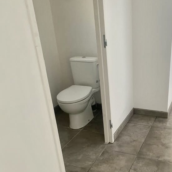 Toilettes rénovées avec carrelage gris au sol et peinture blanche murale – chantier terminé par Michaël David