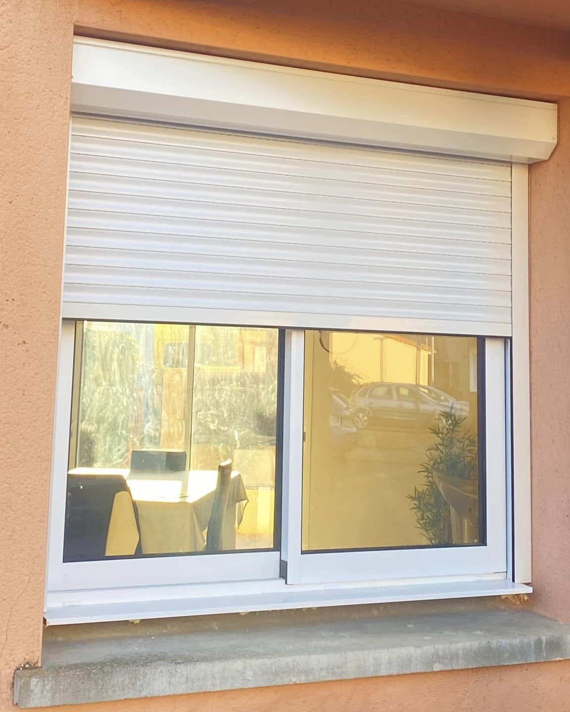 Installation de volet roulant électrique blanc sur façade extérieure avec fenêtre PVC