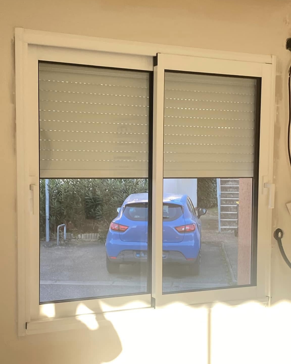 Fenêtre PVC avec double vitrage et volet roulant motorisé en position semi-fermée